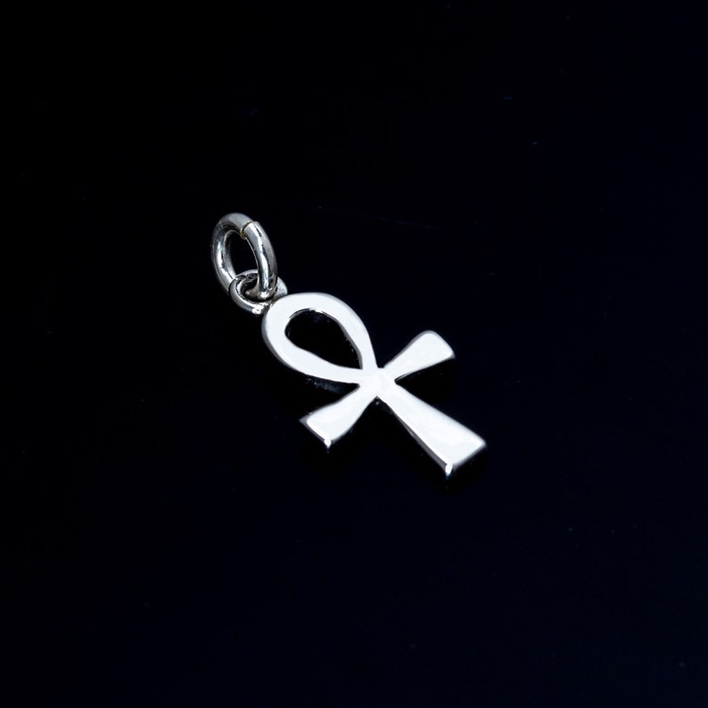K&ouml;nnte beinhalten: Ein silberner Anh&auml;nger in Form eines Ankh. Das Ankh ist ein altes &auml;gyptisches Symbol des Lebens.