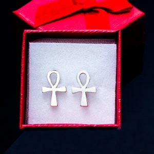 K&ouml;nnte beinhalten: Ein Paar silberne Ankh-Ohrringe in einer roten Geschenkbox. Die Ohrringe sind ein Symbol des ewigen Lebens in der alten &auml;gyptischen Mythologie.