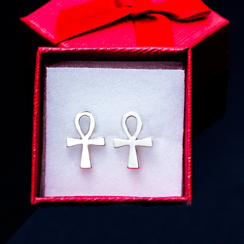 K&ouml;nnte beinhalten: Ein Paar silberne Ankh-Ohrringe in einer roten Geschenkbox. Die Ohrringe sind ein Symbol des ewigen Lebens in der alten &auml;gyptischen Mythologie.