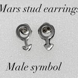 K&ouml;nnte beinhalten: Ein Paar silberne Ohrstecker mit dem m&auml;nnlichen Symbol, auch bekannt als Mars-Symbol. Die Ohrringe befinden sich auf einem wei&szlig;en Hintergrund. Mars Ohrstecker. M&auml;nnliches Symbol.
