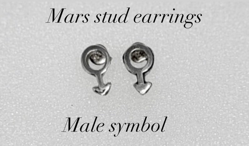K&ouml;nnte beinhalten: Ein Paar silberne Ohrstecker mit dem m&auml;nnlichen Symbol, auch bekannt als Mars-Symbol. Die Ohrringe befinden sich auf einem wei&szlig;en Hintergrund. Mars Ohrstecker. M&auml;nnliches Symbol.