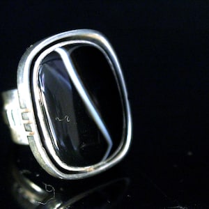 May include: A silver ring with a black and white agate stone set in a bezel setting.
