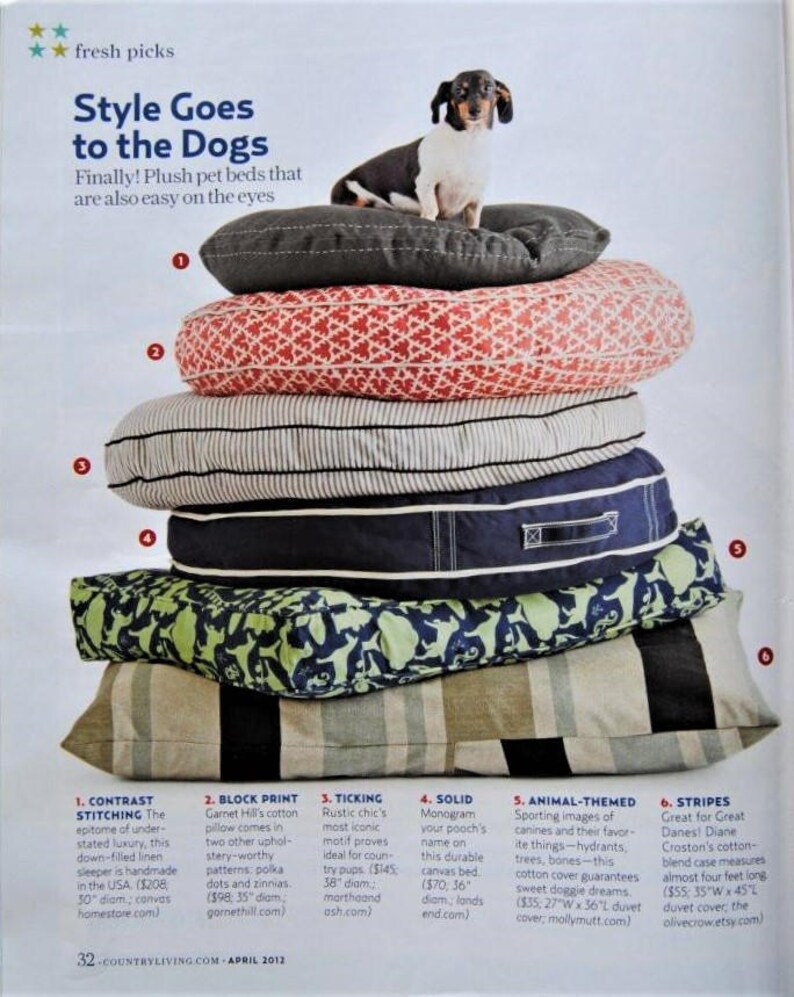 May include: A stack of six different dog beds in various colors and patterns, including stripes, ticking, and animal prints. The beds are made of plush fabrics and are designed to be comfortable for dogs. The text "Style Goes to the Dogs" is visible at the top of the image.