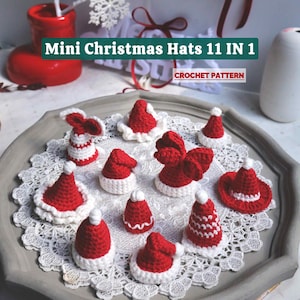 May include: A collection of eleven miniature red and white crocheted Christmas hats, displayed on a decorative lace doily. The hats vary in style, with some featuring white trim and pom-poms. The image includes the text "Mini Christmas Hats 11 IN 1".