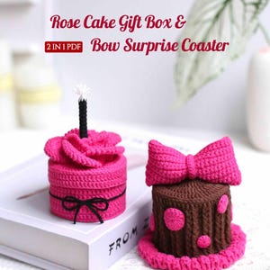 May include: Two crocheted items: a pink rose cake gift box with a black bow and a candle, and a brown cake with a pink bow and polka dots. The text on the image reads "Rose Cake Gift Box & Bow Surprise Coaster".