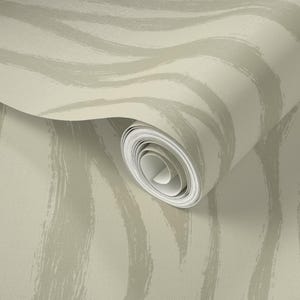 May include: A roll of wallpaper with a neutral color palette. The design features broad, wavy brushstrokes in a lighter shade of beige against a beige background. The paper is partially unrolled, revealing the rolled-up portion.