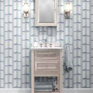 May include: A light wood bathroom vanity with a white marble countertop, two drawers, and an open bottom shelf. Above it is a matching wood medicine cabinet with a mirror, flanked by two wall-mounted sconces with cylindrical glass shades.