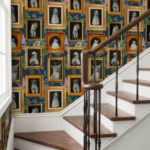 May include: A staircase with a navy blue wallpaper featuring framed portraits of cats in vintage attire. The wallpaper has a floral pattern. The staircase has wooden steps and a dark brown handrail.
