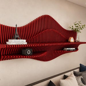 Puede incluir: Un estante de pared rojo que presenta una serie de listones verticales que crean una estructura fluida en forma de onda. El estante tiene dos niveles de almacenamiento, con libros, una réplica de la Torre Eiffel, un reloj y un florero.