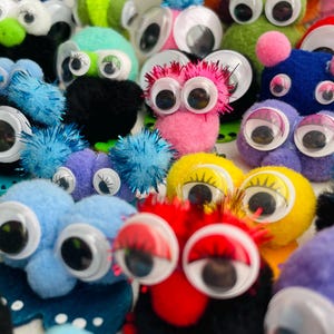 May include: A collection of colorful, fuzzy creatures with large, googly eyes. The creatures are in various colors, including pink, blue, yellow, and green. Some have spiky or fluffy textures, creating a playful and whimsical appearance.