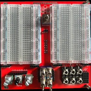 May include: A red Protomato breadboard with three rows of breadboard pins, a power switch, a gate CV switch, three potentiometers labeled "POTS", and eight jacks labeled "JACKS".