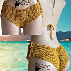 May include: Mustard yellow crochet bikini bottoms with tie sides. The bottoms are displayed on a mannequin with the "Shyler Crochets" logo. The background shows a beach scene with turquoise water and a blue sky.