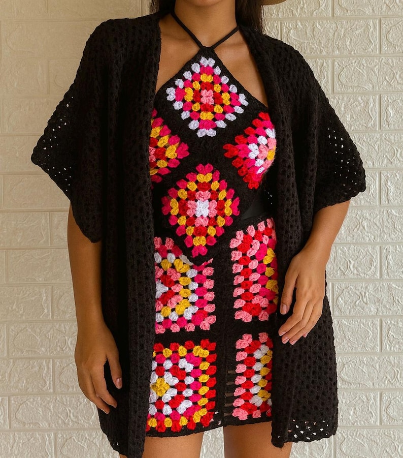 Puede incluir: Un c&aacute;rdigan de crochet negro y un conjunto a juego de top halter y falda. El conjunto presenta un colorido patr&oacute;n de cuadrados de la abuela en rosa, amarillo y blanco sobre un fondo negro. El c&aacute;rdigan tiene mangas cortas.