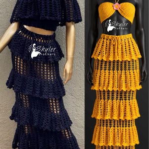Peut inclure: Deux ensembles deux pi&egrave;ces en crochet sur mannequins. L'ensemble de gauche est bleu marine fonc&eacute; avec un haut &agrave; &eacute;paules d&eacute;nud&eacute;es et une jupe longue &agrave; &eacute;tages en maille ouverte. L'ensemble de droite est jaune vif avec un haut dos nu et une fleur rose.