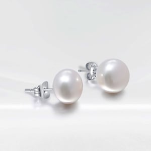 May include: A pair of pearl stud earrings with silver posts. The pearls are white and round.