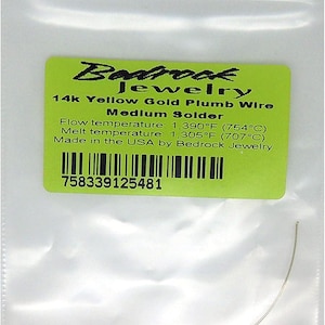 May include: A thin piece of 14k yellow gold plumb wire medium solder in a clear plastic bag with a green label reading Bedrock Jewelry, 14k Yellow Gold Plumb Wire, Medium Solder, Flow temperature 1,390°F, Melt temperature 1,305°F, Made in the USA.