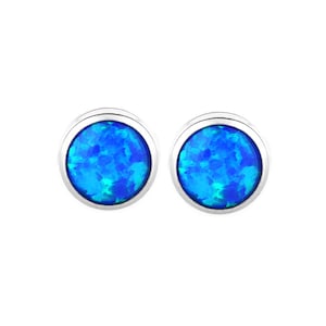 May include: A pair of round stud earrings featuring vibrant blue opal stones set in polished silver-toned metal bezels. The circular stones display a mottled, iridescent pattern with varying shades of bright blue and hints of lighter cyan throughout.