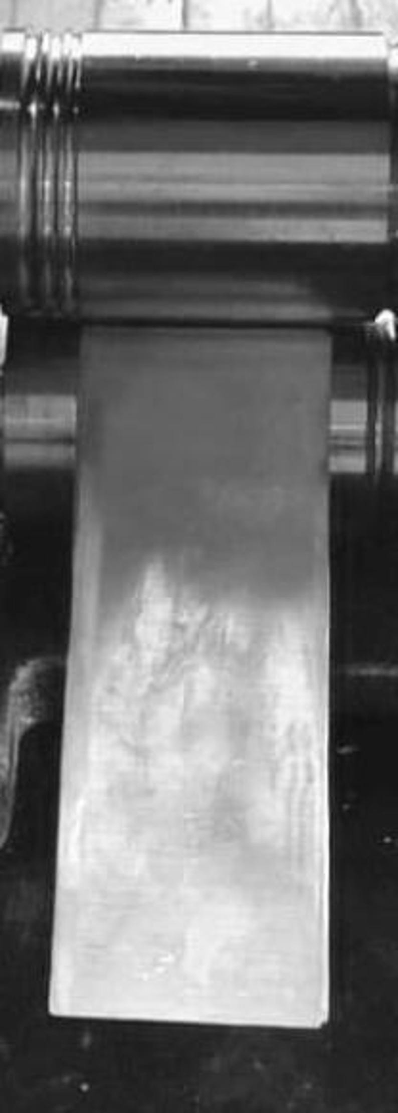 Puede incluir: Primer plano de un rodillo met&aacute;lico utilizado en una prensa de impresi&oacute;n. El rodillo est&aacute; cubierto con una fina capa de tinta, que se est&aacute; transfiriendo a una hoja de papel.