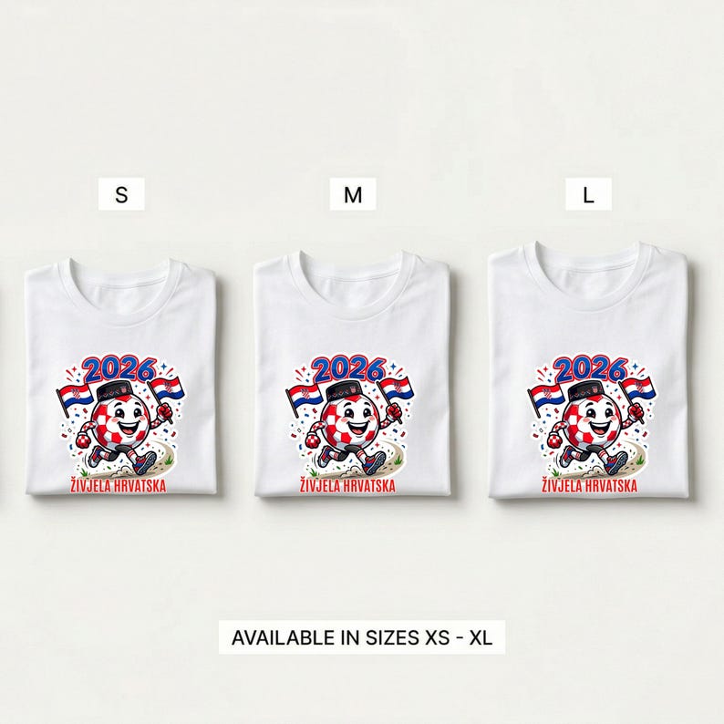 Pode incluir: T-shirts brancas com um design de personagem de bola de futebol. O design inclui o ano "2026", bandeiras croatas e o texto "ŽIVJELA HRVATSKA". Dispon&iacute;vel nos tamanhos XS a XL.