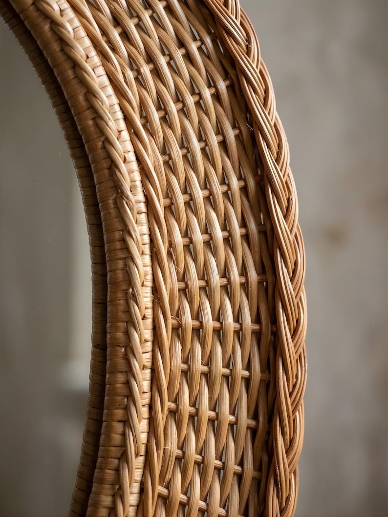 May include: A round mirror featuring a light brown woven wicker frame. The frame displays a detailed lattice pattern with a thick, braided border along the outer and inner edges, showcasing the natural texture and tan colour of the material.