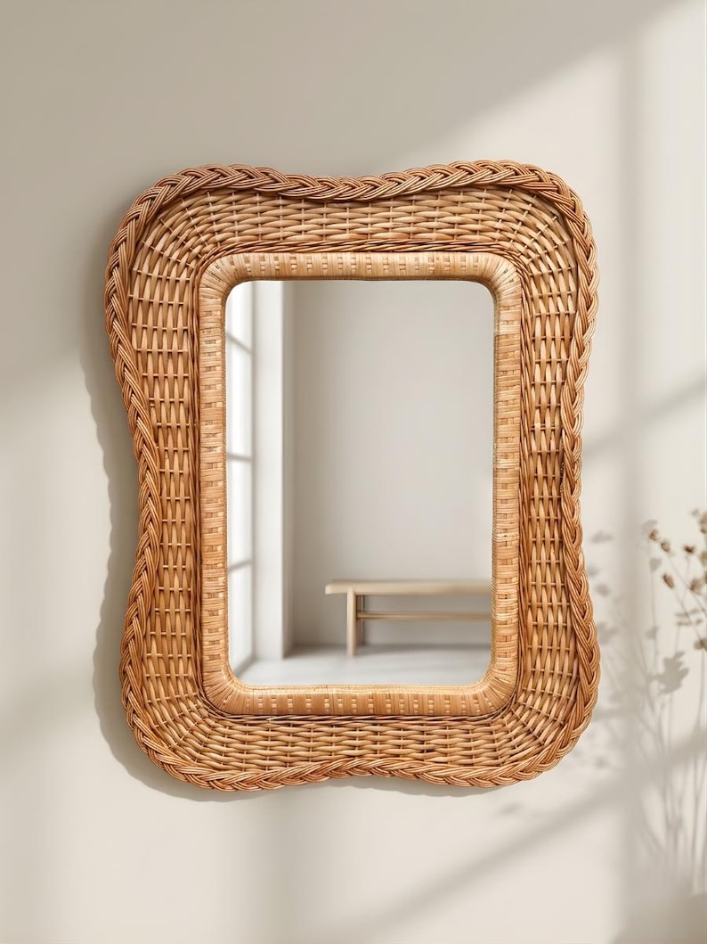 May include: A rectangular wall mirror featuring a light brown woven rattan frame with a wavy, organic edge. The frame consists of multiple layers of intricate wicker detailing, surrounding a clear, reflective glass centre surface.