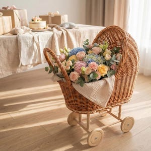 May include: A wicker pram filled with a vibrant floral display. The arrangement features pink, yellow, and blue roses and hydrangeas. The pram has wooden wheels and a handle. A white cloth lines the pram.