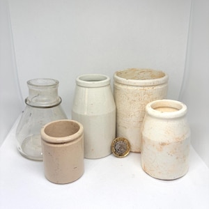 May include: A white ceramic mug with a black handle and the text "But First, Coffee" in a black, handwritten-style font. The mug is on a white surface.