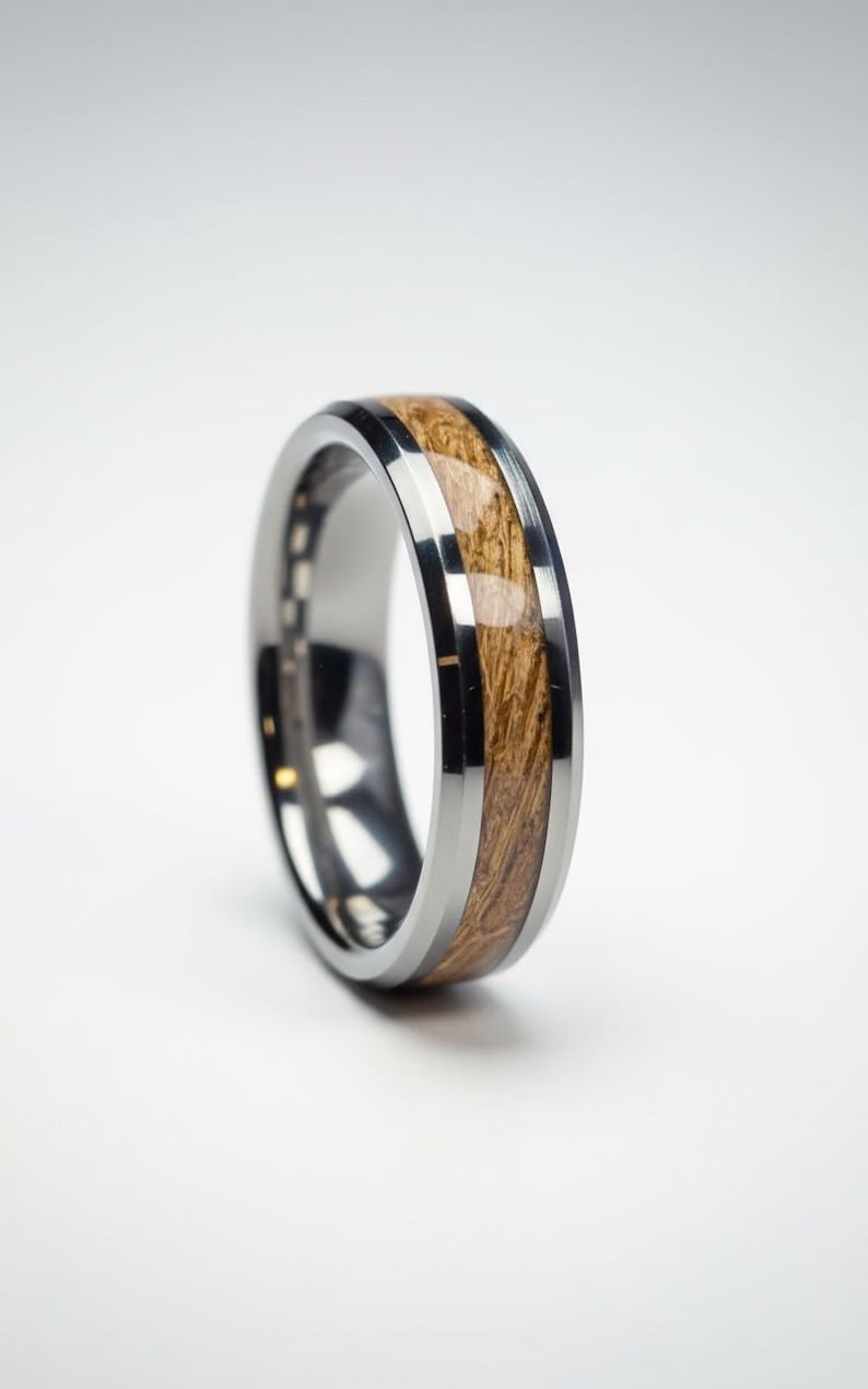 May include: A silver-colored ring with a wood inlay. The ring features a polished, metallic band with a central inlay of light brown wood. The wood grain is visible, adding texture and warmth to the design. A modern piece of jewelry.
