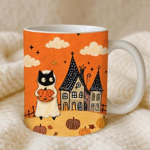 Puede incluir: Una taza de cer&aacute;mica blanca con un fondo naranja vibrante que muestra un gato negro disfrazado de fantasma sosteniendo una calabaza. La ilustraci&oacute;n incluye una casa de techos puntiagudos, calabazas dispersas, peque&ntilde;as nubes y estrellas.
