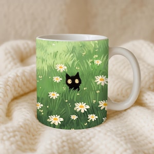 May include: White ceramic mug featuring a whimsical illustration of a black cat peeking through a field of daisies. The background is a vibrant green, with white and yellow flowers scattered throughout. The mug has a curved handle.