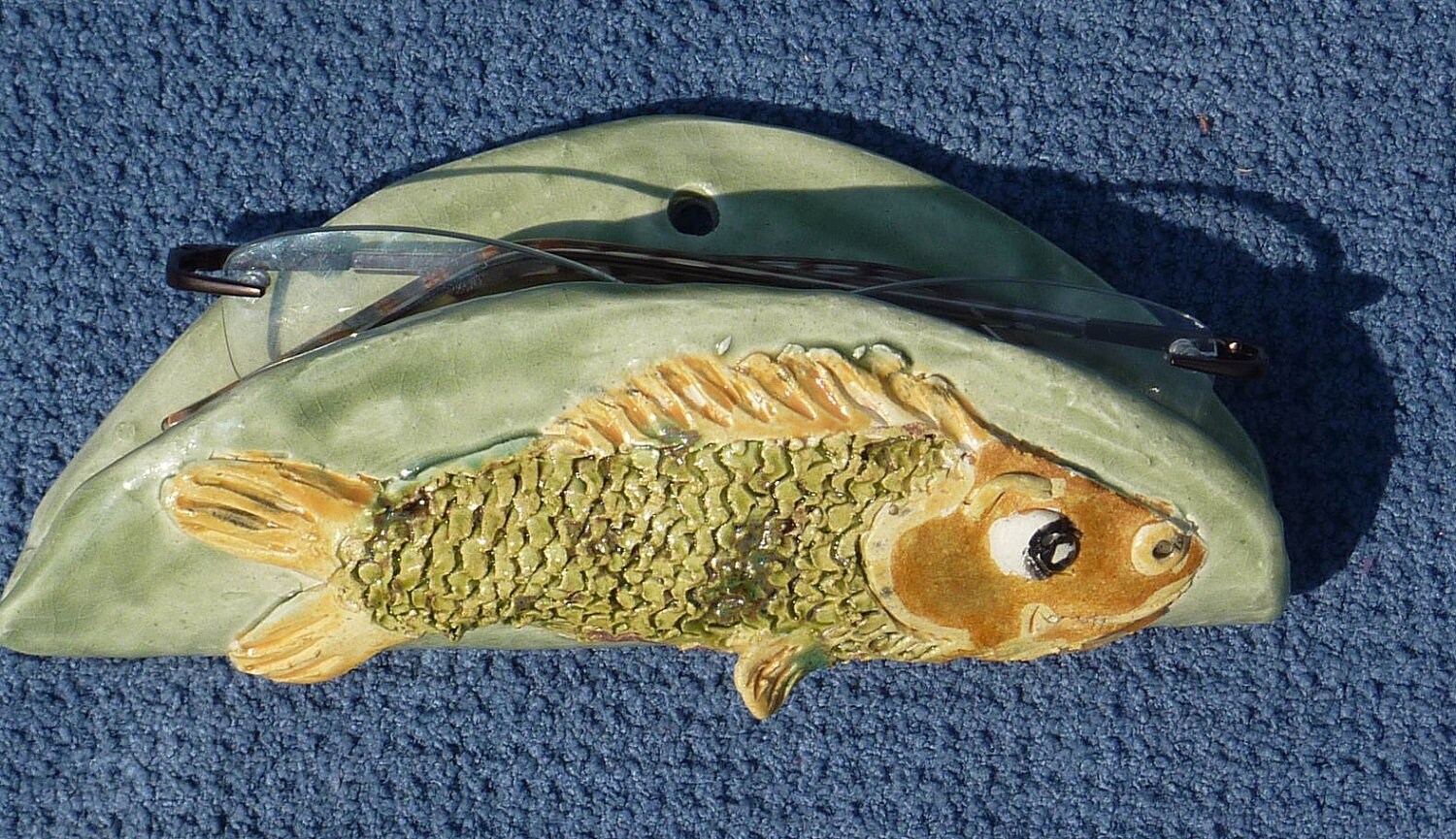 Fish eye glass case or holder handmade in USA from a lump of clay no molds are ever used, hangs on wall.
