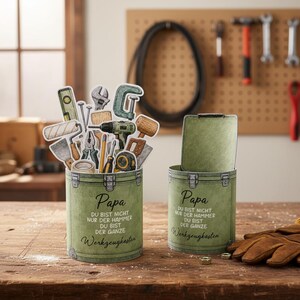 Puede incluir: Dos cajas de herramientas verdes con la palabra "Papa" y texto en alem&aacute;n. Una caja de herramientas est&aacute; llena de pegatinas de herramientas. La otra caja de herramientas tiene la tapa abierta. El texto en la caja de herramientas dice "DU BIST NICHT NUR DER HAMMER DU BIST DER GANZE Werkzeugkasten."