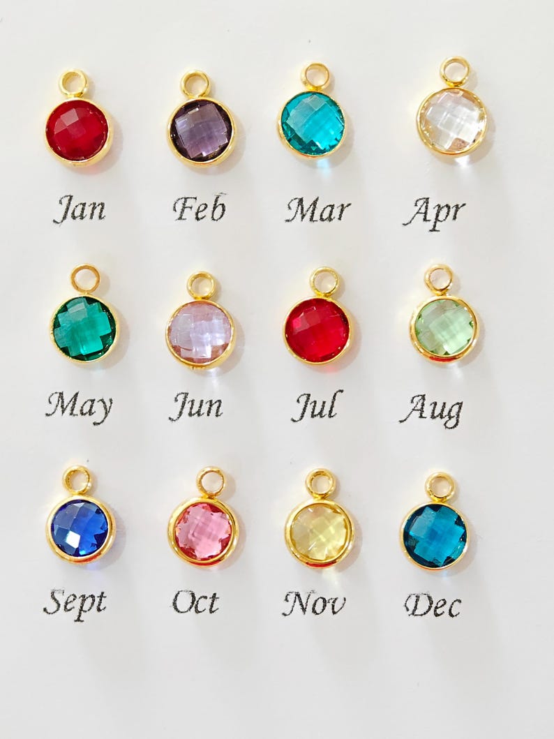 May include: Twelve gold-colored pendants with colorful, faceted gemstones, each representing a month of the year. The months are labeled Jan, Feb, Mar, Apr, May, Jun, Jul, Aug, Sept, Oct, Nov, and Dec.