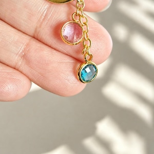 Puede incluir: Un componente de pulsera o collar de eslabones de metal dorado con dos piedras redondas facetadas en engaste de bisel. Una piedra es de color rosa transl&uacute;cido p&aacute;lido y la otra es de un azul transl&uacute;cido vibrante, suspendidas de una cadena dorada.