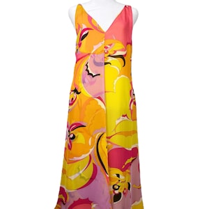 May include: A sleeveless, floor-length dress with a V-neckline. The dress features a vibrant, abstract floral pattern in shades of orange, yellow, pink, and black. The fabric appears to be lightweight, with a flowing silhouette.
