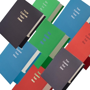 May include: A collection of hardcover journals in various colors including black, blue, green, and red. Each journal features a solid-colored cover with the text "Your Custom Text Here" printed in a contrasting color on the front center.