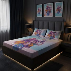 Op de afbeelding: Een bed met een hoeslaken en twee kussenslopen met een kleurrijk cartoonontwerp. Het ontwerp bevat meerdere personages in verschillende poses. Drie ingelijste posters met vergelijkbare kunstwerken hangen boven het bed.