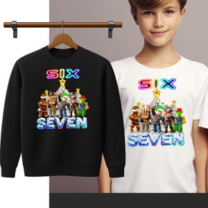 Könnte beinhalten: Schwarzes Sweatshirt und weißes T-Shirt mit dem Wort "SIX" in Regenbogenfarben über einer Gruppe von Cartoon-Figuren. Das Wort "SEVEN" steht unter den Figuren in blauer Schrift. Ein junger Mensch trägt das T-Shirt.