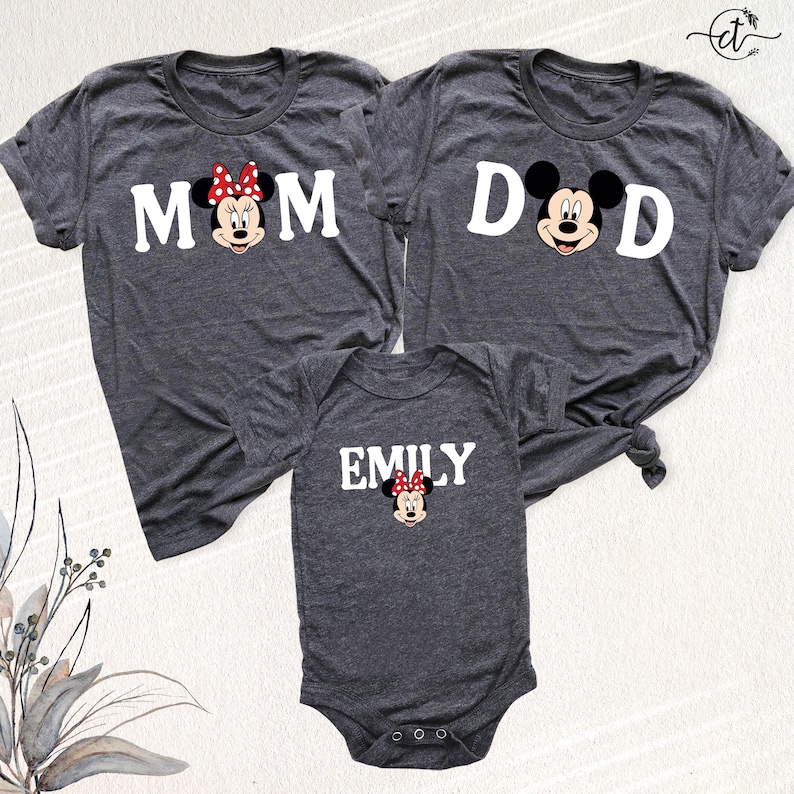 Puede incluir: Tres camisetas grises oscuras y un body para beb&eacute; con Minnie Mouse de Disney. Las camisetas dicen "MOM" y "DAD" con gr&aacute;ficos de Minnie y Mickey Mouse. El body dice "EMILY" con un gr&aacute;fico de Minnie Mouse. Ropa a juego para la familia.