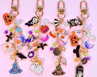 May include: Four gold-toned metal keychains featuring assorted Halloween-themed enamel charms including pumpkins, ghosts, bats, witches' hats, a tombstone with the text RIP, and colorful beads attached to gold chains with lobster claw clasps.
