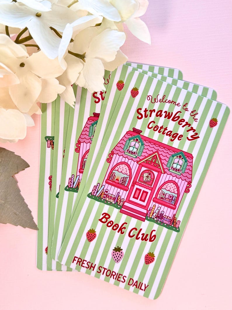 several identical bookmarks with a pink cottage design sits on pink background with florals peaking from corner. The card reads "Welcome to the Strawberry Cottage Book Club, Fresh Stories Daily" and features strawberries and green stripes, creating a whimsical and inviting feel.