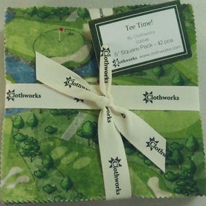 May include: A stack of 42 fabric squares, each measuring 5 inches, featuring a green golf course print. The stack is tied with a white ribbon printed with the Clothworks logo and includes a label reading Tee Time! By Clothworks SQ0546.