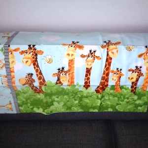 May include: A blue and green fabric panel with a repeating pattern of giraffes peeking out from behind green bushes. The giraffes have brown spots and are looking in different directions. There are also small yellow bees flying around the giraffes.