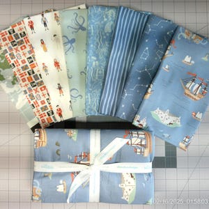 K&ouml;nnte beinhalten: Ein Set aus zehn Stoffquadraten mit verschiedenen nautischen Motiven. Die Quadrate sind in Blaut&ouml;nen, Wei&szlig; und Rot gehalten und zeigen Illustrationen von Schiffen, Sternen und anderen nautischen Motiven.