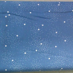 May include: Blue fabric with a white polka dot pattern. The dots are of varying sizes and are scattered randomly across the fabric.