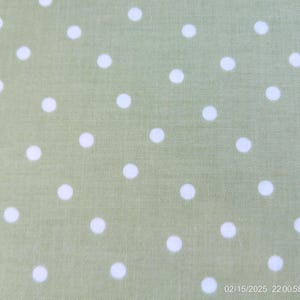 May include: A green fabric with a white polka dot pattern. The fabric has a subtle texture.