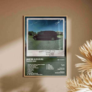 Puede incluir: Póster enmarcado con la portada del álbum "good kid, m.A.A.d city" de Kendrick Lamar. La imagen muestra una furgoneta oscura contra un fondo suburbano. El póster incluye la lista de canciones del álbum y detalles de lanzamiento.
