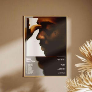 May include: Framed poster featuring a profile of a person with a cross tattoo, with the text "Icon Brent Faiyaz" and a tracklist. The poster has a wooden frame and is displayed against a neutral wall. The poster includes the release date and run time.