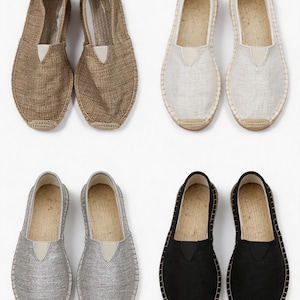 K&ouml;nnte beinhalten: Vier Paar Espadrilles zum Hineinschl&uuml;pfen, angeordnet in einem Raster. Das Paar oben links ist braun, oben rechts wei&szlig;, unten links silber und unten rechts schwarz. Jeder Schuh verf&uuml;gt &uuml;ber ein Obermaterial aus gewebtem Stoff und eine Sohle aus Jutekordel.