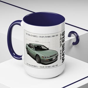 May include: White ceramic mug with a navy blue interior and handle. The mug features a light green car illustration with text that reads "S13 SILVIA" and specifications. The mug is a great gift for car enthusiasts.